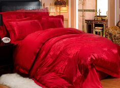 a red comforter set on a bed in a room with white fur rugs