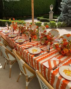 an orange and white striped table cloth is set with place settings for the dinner party