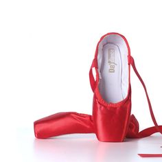 a pair of red ballet shoes sitting on top of a white floor next to a ribbon