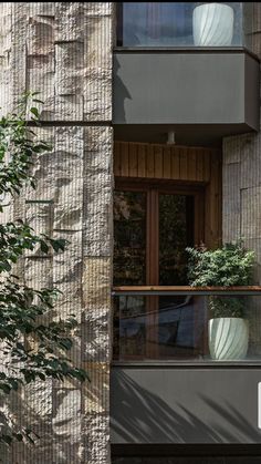 an apartment building with two balconies on the second floor and plants in the window