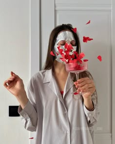 a woman wearing a mask and holding a cupcake in front of her face with red hearts coming out of it