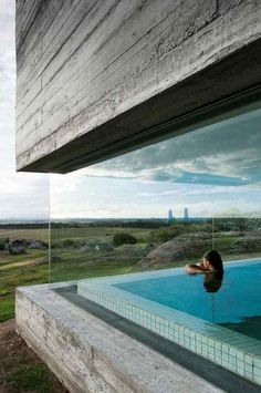 a woman is sitting in the pool looking out at the view from her house's window