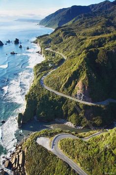 an aerial view of a winding road next to the ocean