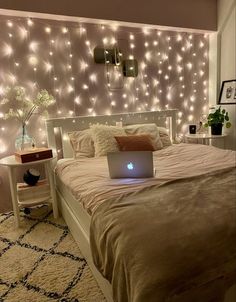 a laptop computer sitting on top of a bed in front of a wall with lights