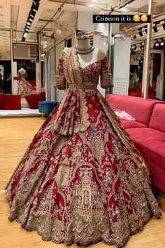 a red and gold wedding gown on display in a storeroom with mannequins