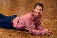 a man laying on the floor with his legs spread out and smiling at the camera