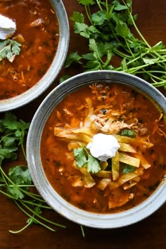 two bowls of chili soup with sour cream and cilantro garnishes