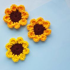 three crocheted sunflowers on a blue surface