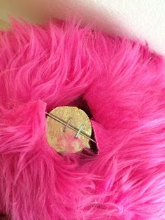 a pink stuffed animal with a button on it's side