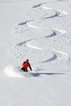 a man riding skis down the side of a snow covered slope on a snowy slope