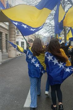 two girls walking down the street holding flags