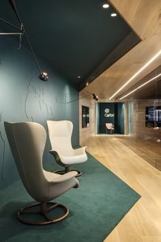 a chair and ottoman in an office with wood flooring, blue walls and green carpet