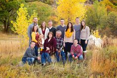 a group of people posing for a photo in a field with trees and rocks behind them