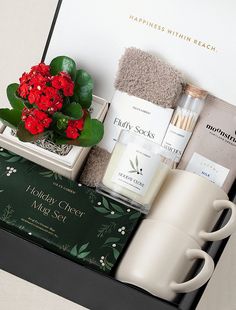 a gift box with red flowers and personal care items in it, including a coffee mug