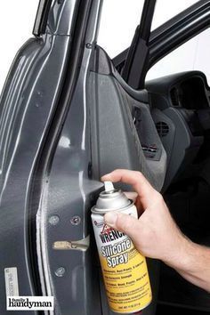 a man is cleaning the inside of a car door with a spray bottle on it