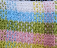 a crocheted blanket that is laying on top of a tablecloth with the colors of blue, green, pink, yellow and white