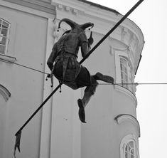 a black and white photo of a man on a tightrope in front of a building