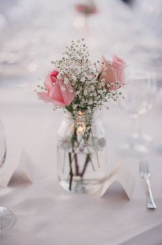 a vase filled with flowers sitting on top of a table next to glasses and silverware