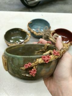 a person is holding a bowl with flowers on it and other bowls in the background