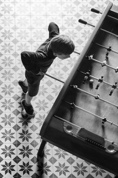 a young boy playing with an old foo - ball table