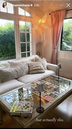 a coffee table with magazines on it in front of a large window and a couch