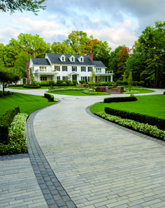 a large white house sitting on top of a lush green field next to a driveway