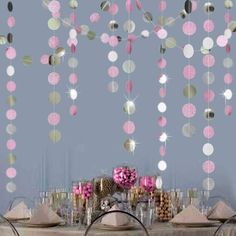 the table is set for a party with pink and gold decorations hanging from the ceiling