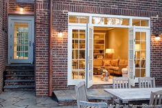 an outside patio with table and chairs next to brick building at night, lit by lights