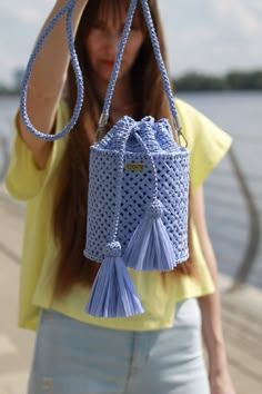 a woman holding up a blue purse with tassels