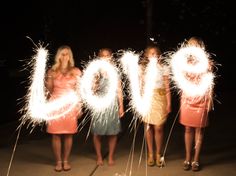 four girls holding sparklers that spell out the word love