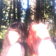 two women standing next to each other in front of trees and sunlight shining on them