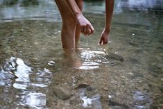 a person standing in shallow water with their feet up