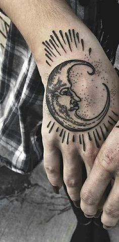 a man's hand with a tattoo on it that has the moon and sun in it