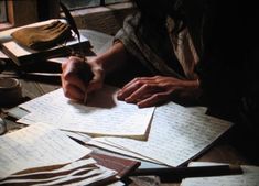 a person sitting at a table with lots of papers and pens in front of them