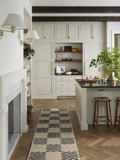 a kitchen with white cabinets and an area rug in front of the stove top oven