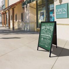 an open sign on the sidewalk in front of a coffee shop