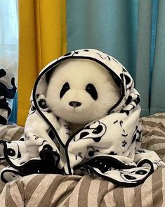 a panda bear wrapped in a blanket on top of a bed