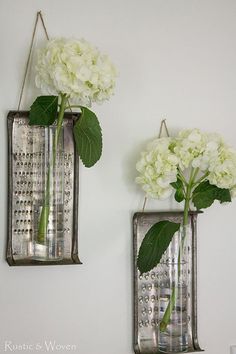 two vases with white flowers are hanging on the wall next to each other,