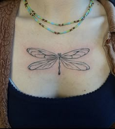 a woman's chest with a dragonfly tattoo on her left side ribcage