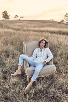 a woman is sitting on a chair in the middle of a field with tall grass