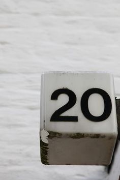 a close up of the number twenty on a metal pole with snow in the background