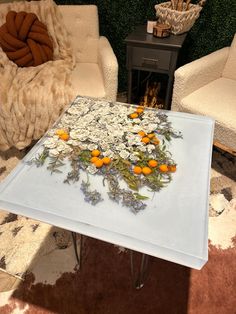 a table that has flowers on it in the middle of two chairs and a rug