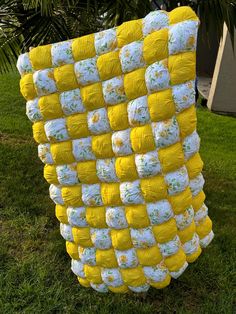 a yellow and white quilt is on the grass