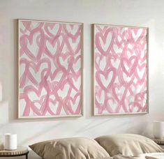 two pink paintings hanging on the wall above a bed