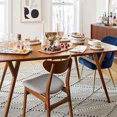 a dining room table is set with plates and glasses on it, next to a blue chair