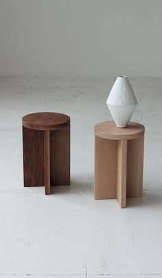 two wooden stools sitting next to each other on top of a white flooring