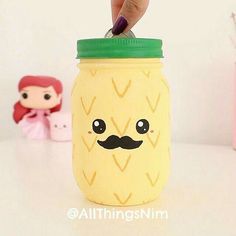 a pineapple mason jar with a fake mustache on it and a little doll in the background