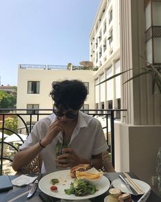 a person sitting at a table with food and drinks in front of them on a balcony