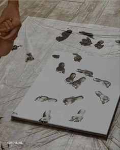 an open book sitting on top of a wooden floor covered in animal tracks and footprints