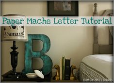 the letter b is next to a lamp and other items on a table in front of a bed